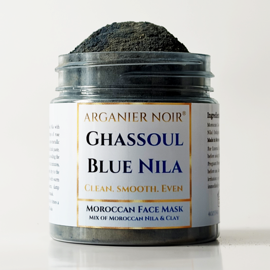 A jar of Arganier Noir Ghassoul Blue Nila Moroccan Face Mask, showing the dark powder piled on top of the open jar, set against a clean white background.